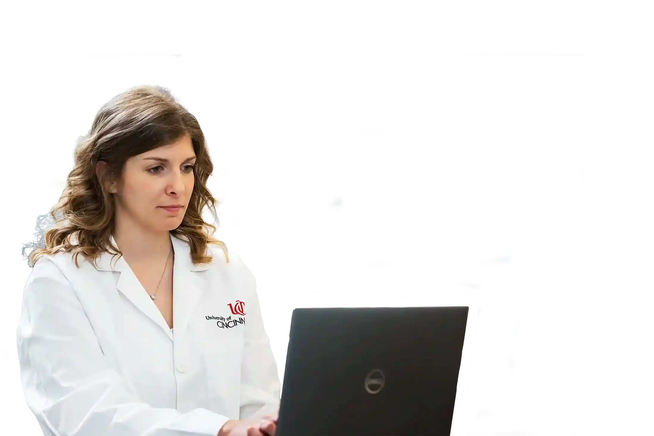 UC co-op student in a labcoat works on a laptop