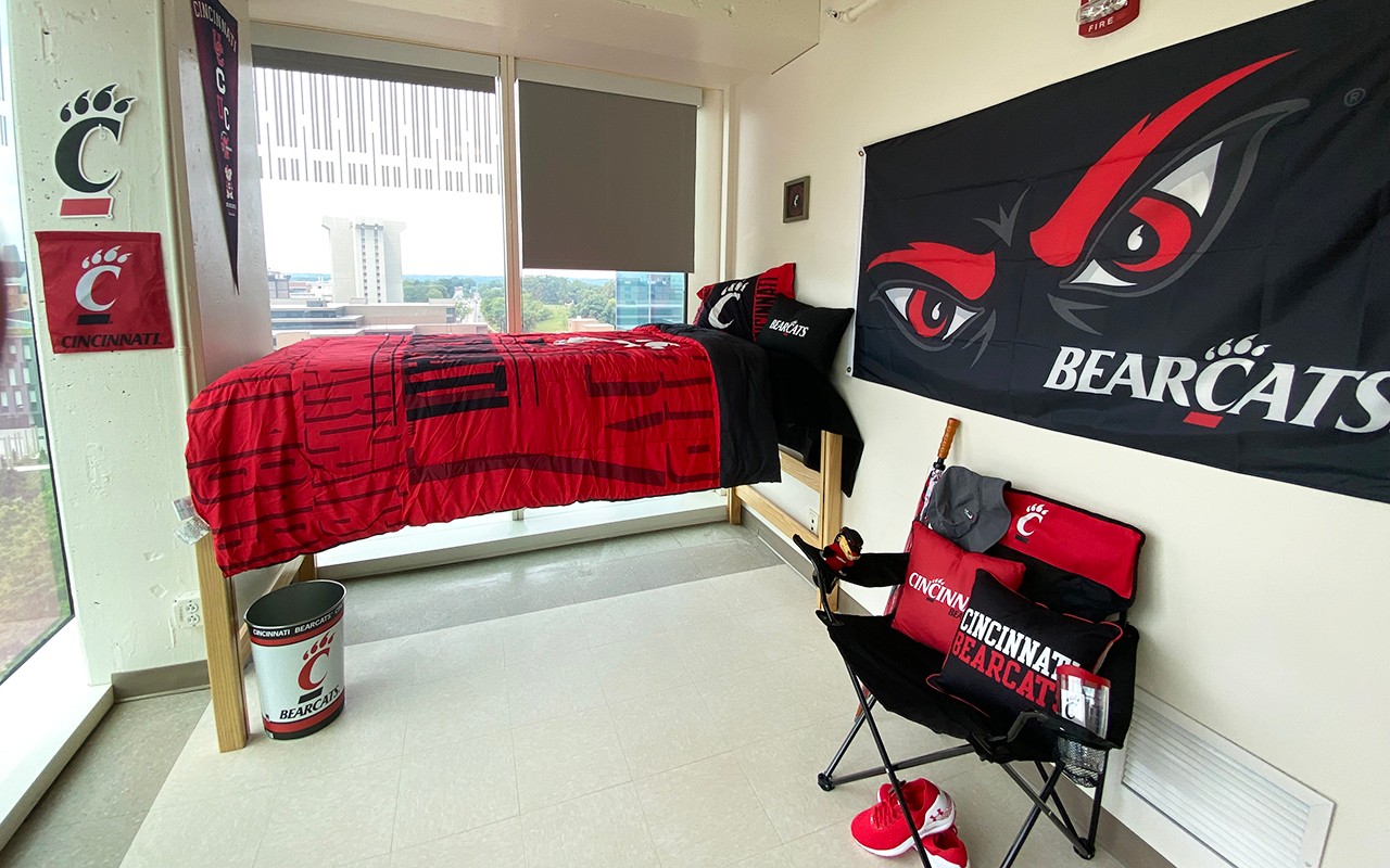 Residence hall room decorated with Bearcats flags, posters, blankets, pillows and a view of the campus.