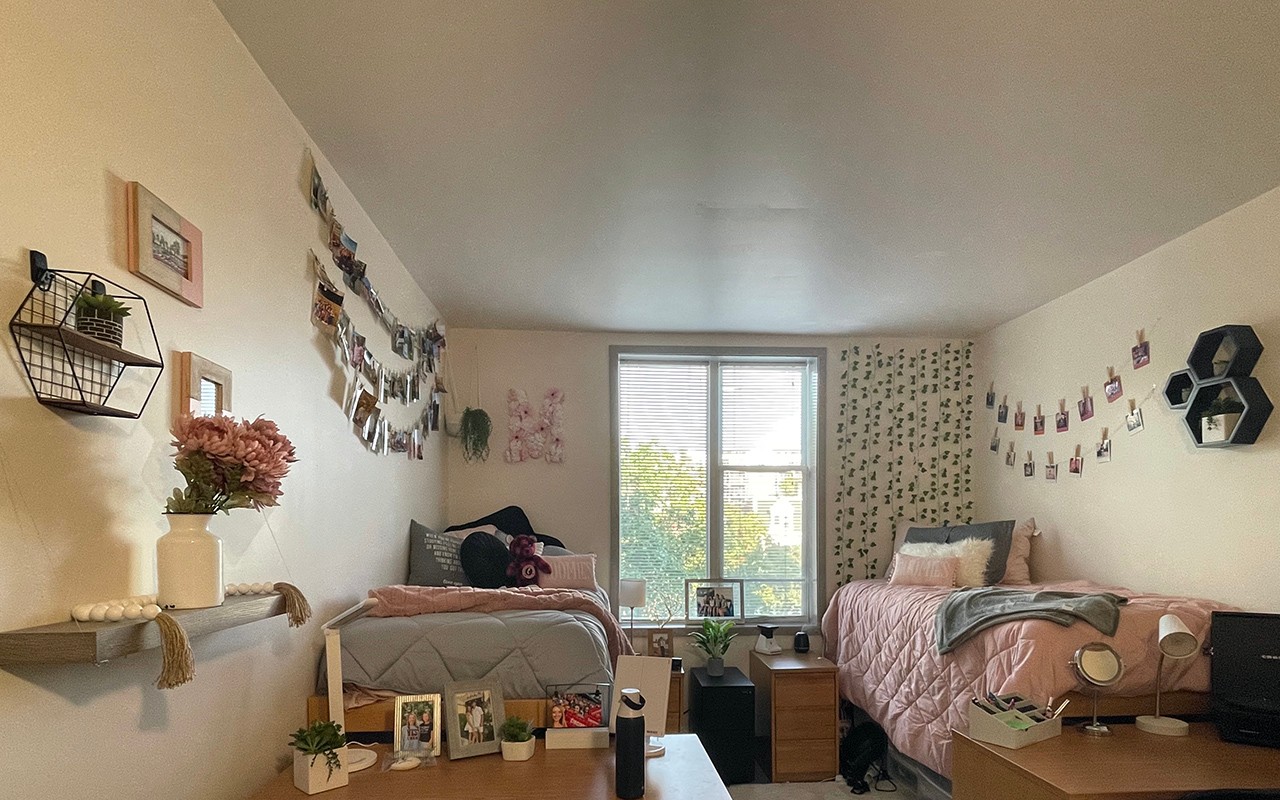 Residence hall bedroom decorated in gray and pink with accent decor and photos on walls