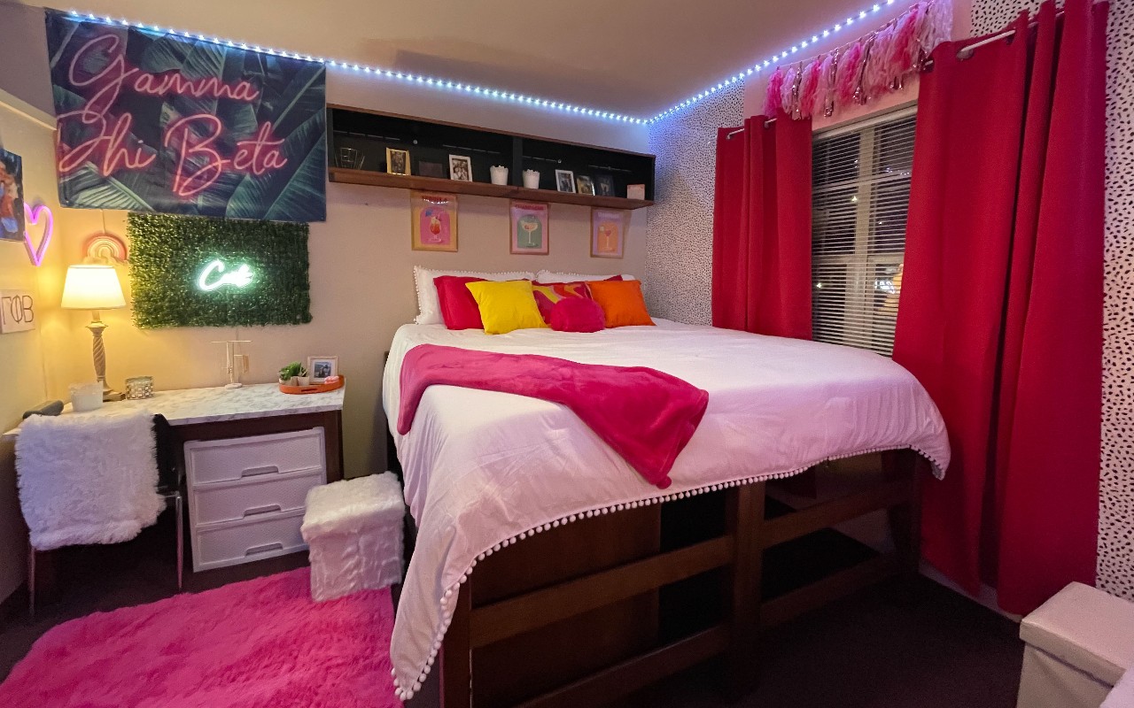 Room decorated with red, pink and yellow. Rug on the floor and light strips around the ceiling