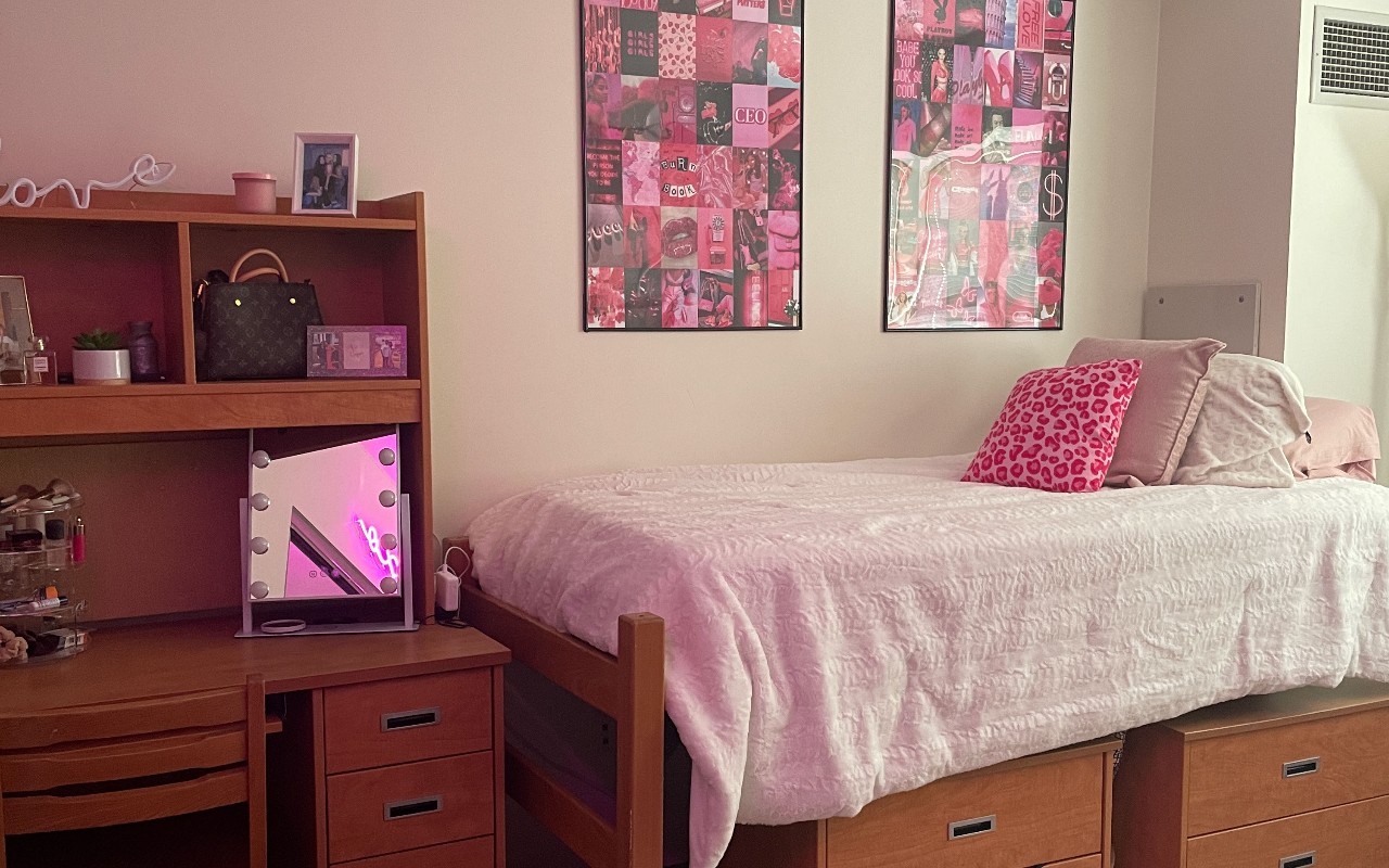 Wbed with white linens and pink accents with framed graphic images on the wall