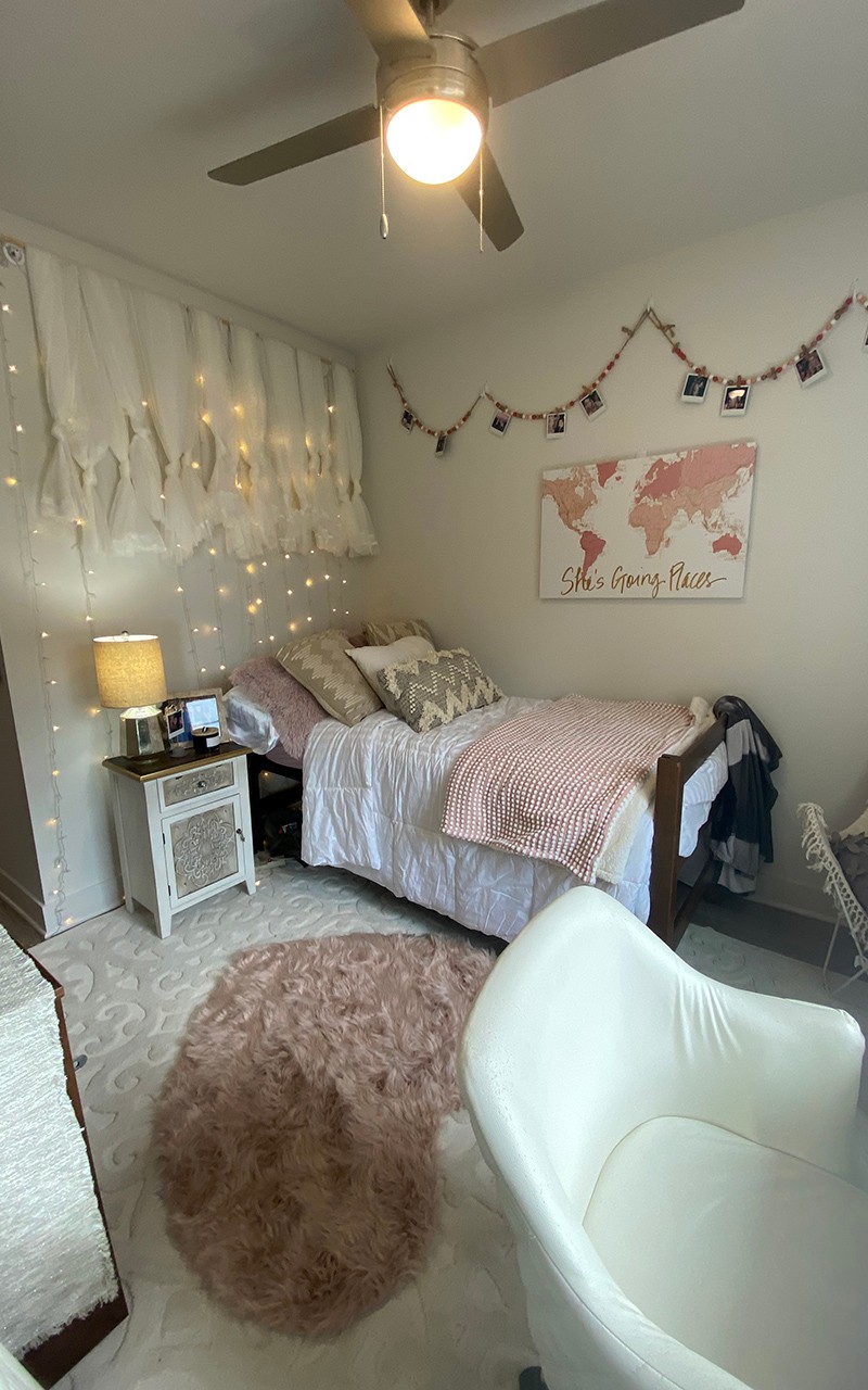 Residence hall bedroom featuring heart throw rug on floor with gray and rose accented art and accessories