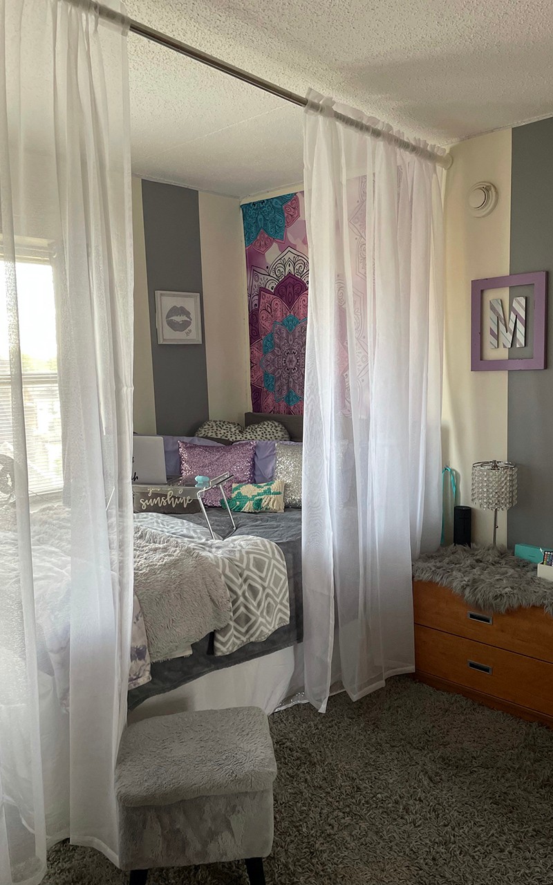 Apartment with bed placed next to window and sheer curtains hanging in front of it