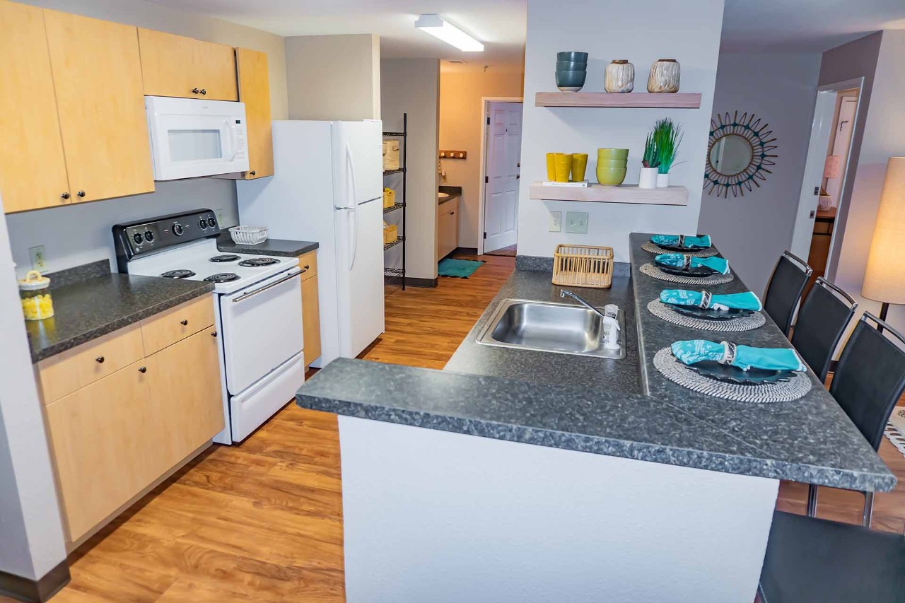 Kitchen featuring refrigerator, stove, microwave with ample counter space and cabinets.